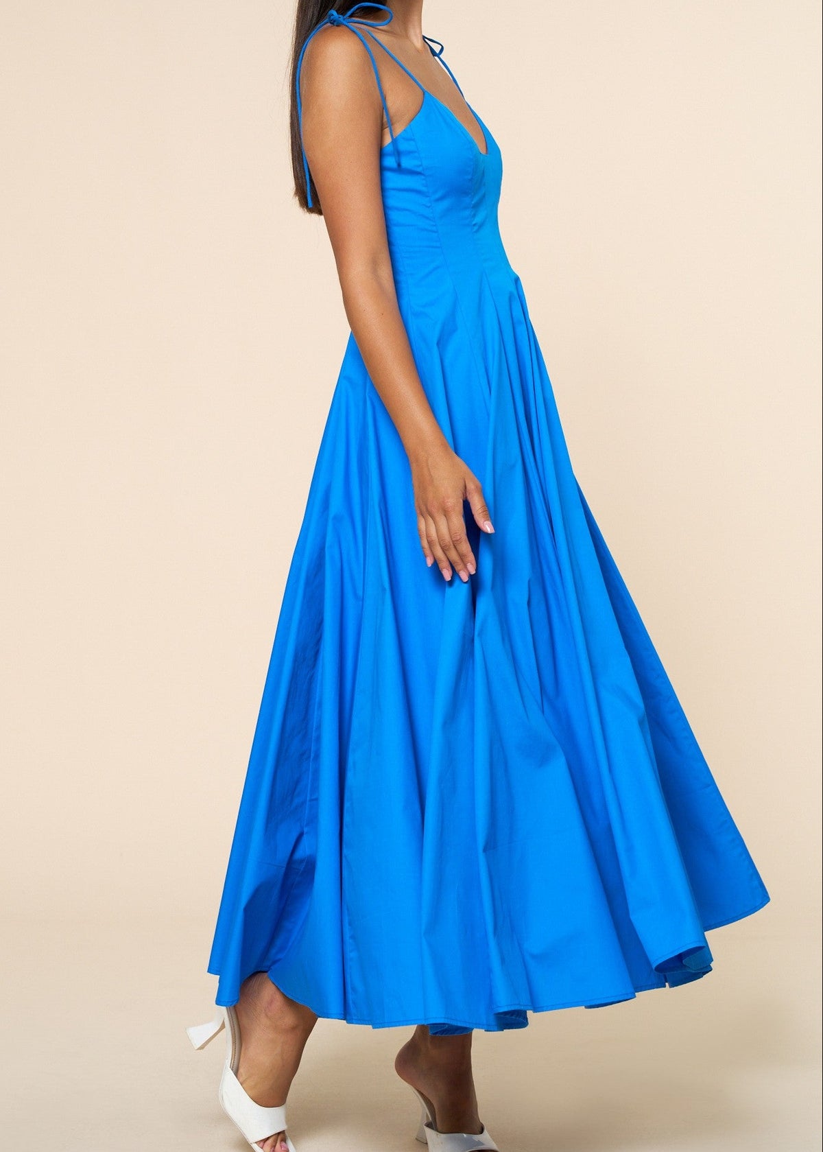 Woman wearing a blue dress against a beige background