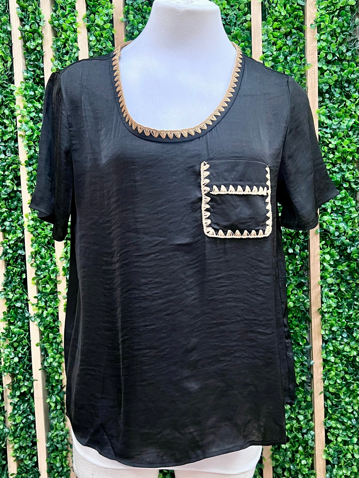 Black top with decorative whipstitch neckline and pocket front view.